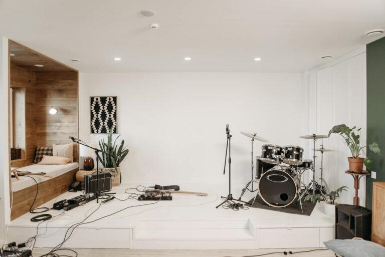 A modern music studio featuring a drum set, guitar, and cozy seating area for musicians.