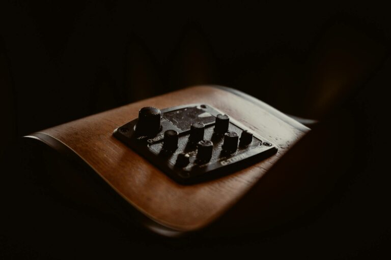 A moody close-up of guitar controls on a wooden body, emphasizing music technology.