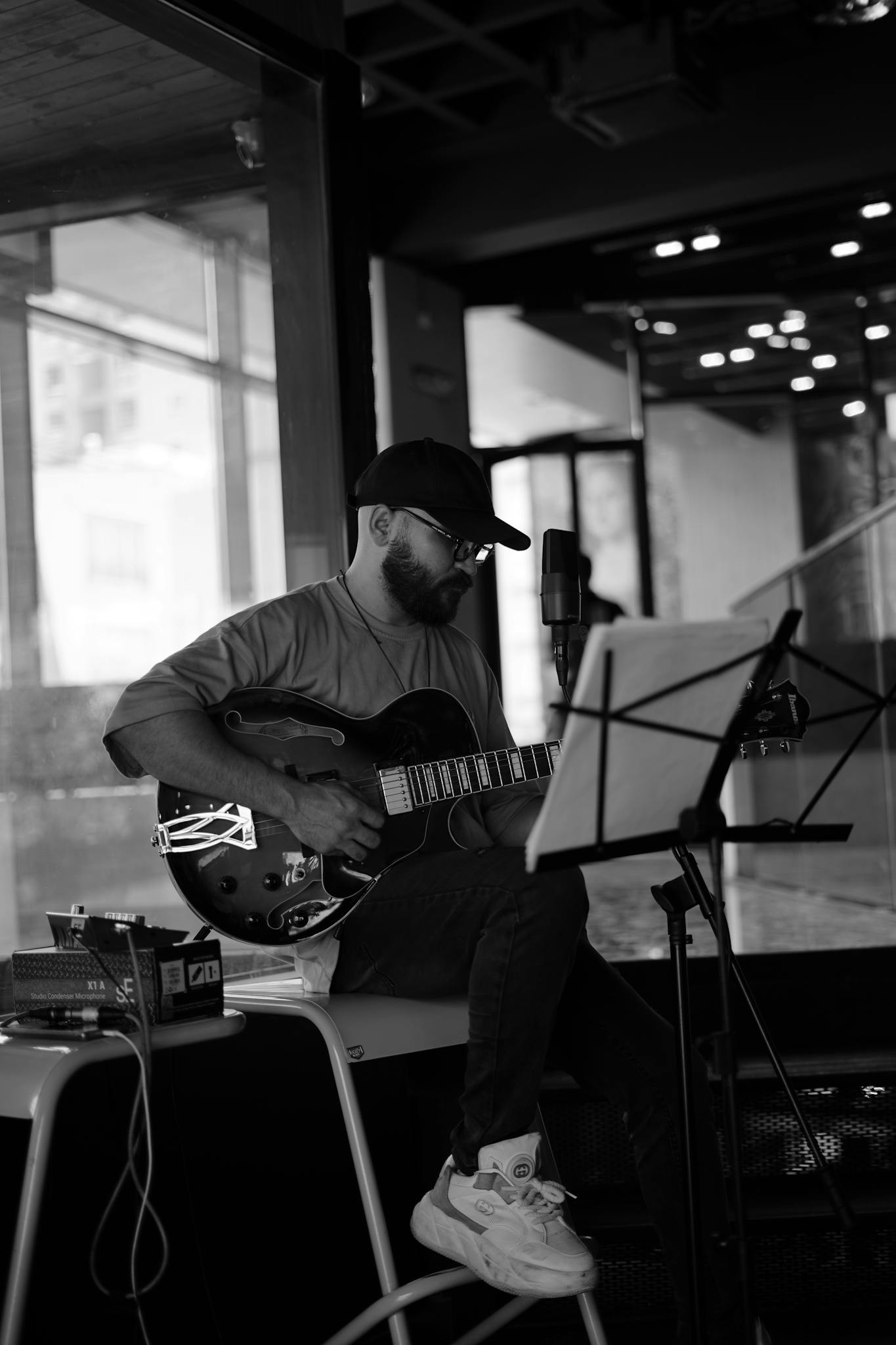 A musician playing an electric guitar indoors in a modern studio setting.