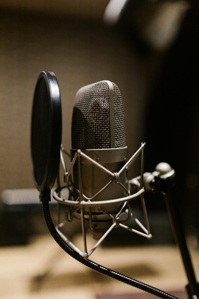 Close-up of a condenser microphone with pop filter in a recording studio setting.